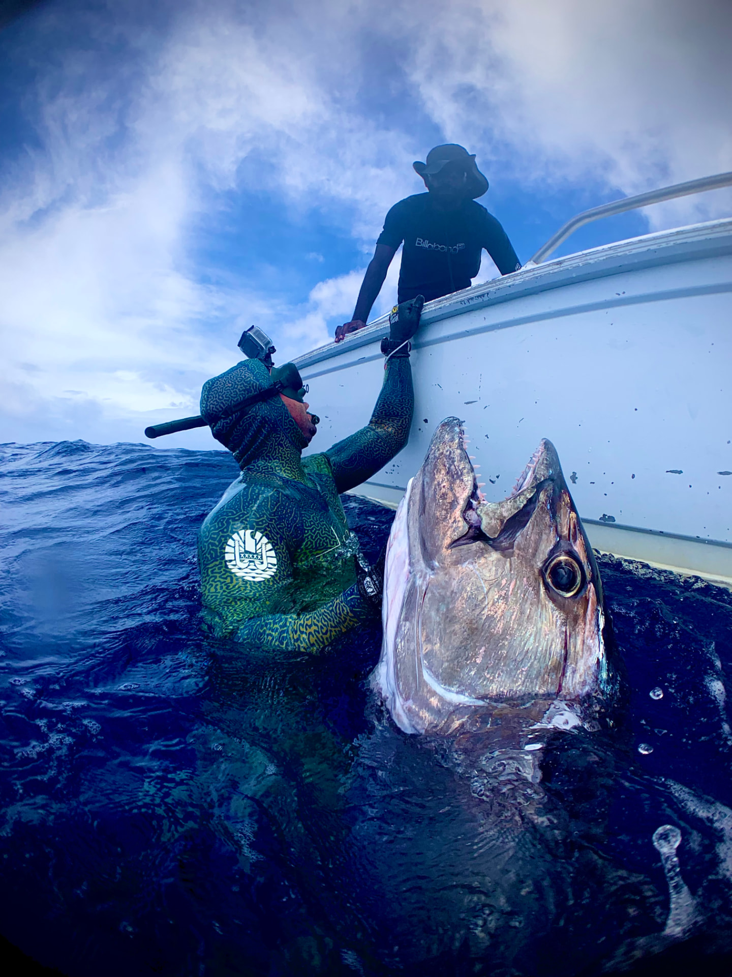 Spearfisher handing a dogtooth tuna up to the boat